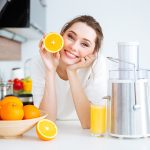 Dona in una cucina domestica che si nutre di acido ascorbico, ovvero vitamina C, attraverso una spremuta di arancia fatta in casa