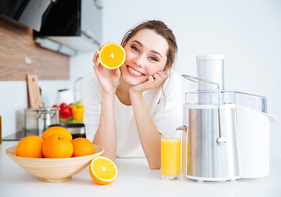 Dona in una cucina domestica che si nutre di acido ascorbico, ovvero vitamina C, attraverso una spremuta di arancia fatta in casa