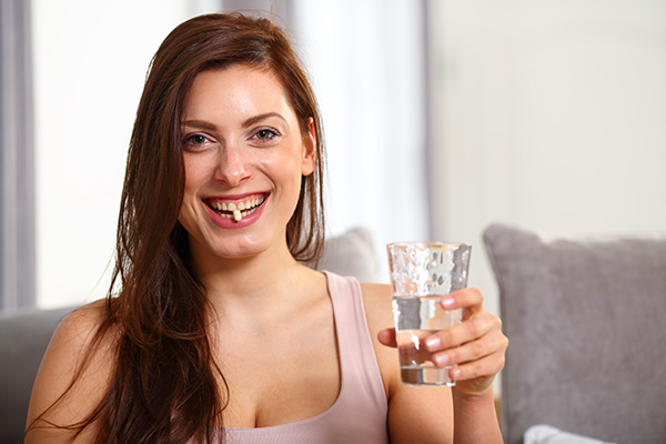 Donna sorridente a casa che ottiene benefici dalla vitamina C grazie all’assunzione di integratori