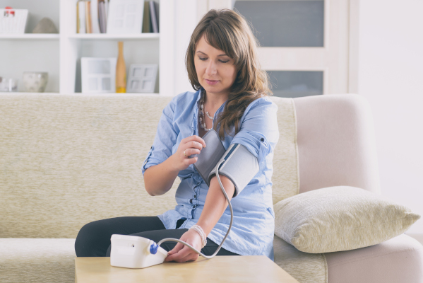 Donna che si misura la pressione arteriosa per prevenire malattie cardiovascolari