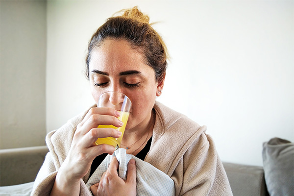 Donna a casa che si riabilita dall’influenza consumando una bevanda naturale ricca di vitamina C
