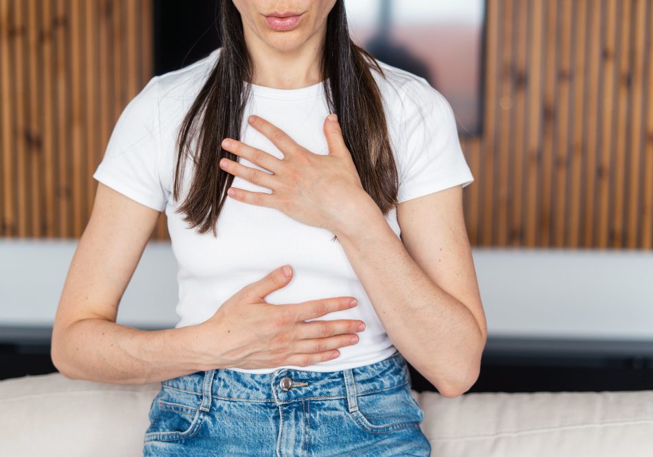 Giovane donna con le mani sul petto sente dolore al petto, tra i sintomi della tachicardia
