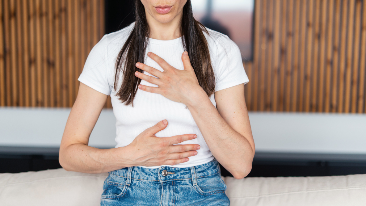 Giovane donna con le mani sul petto sente dolore al petto, tra i sintomi della tachicardia