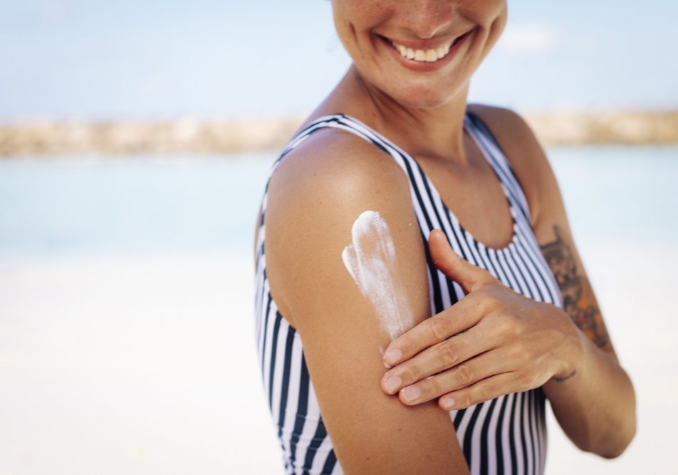 Donna al mare si spalma la crema per proteggere la pelle e prevenire melanoma benigno