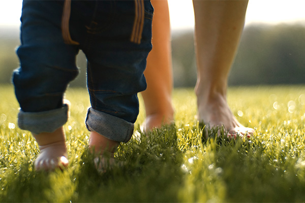 Mamma e bambino che svolgono barefooting sull’erba, vivendo un’esperienza di connessione con la natura