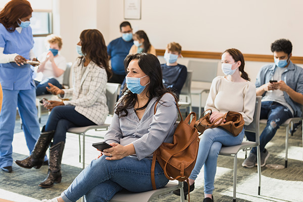 Gruppo di pazienti in sala d’attesa che attende seduto il proprio turno, mantenendo la distanza di sicurezza per evitare la diffusione del coronavirus