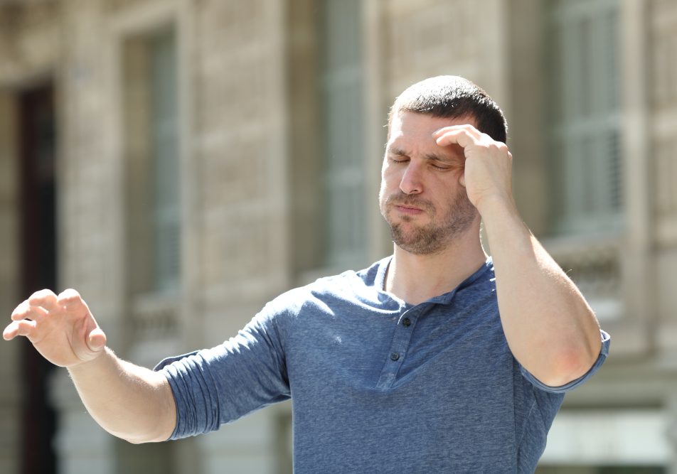 Uomo che, mentre cammina per la strada, avverte ansia e giramenti di testa