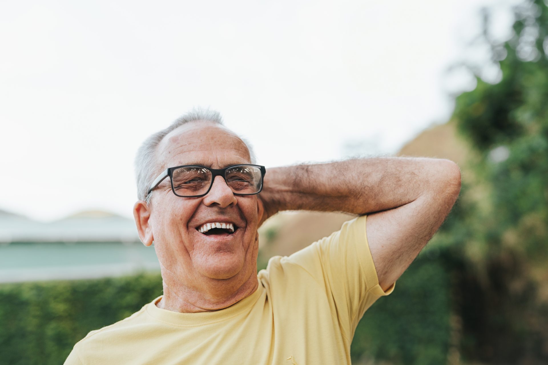 uomo anziano con maglietta gialla e occhiali ride