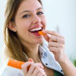 donna sorridente che mangia una carota