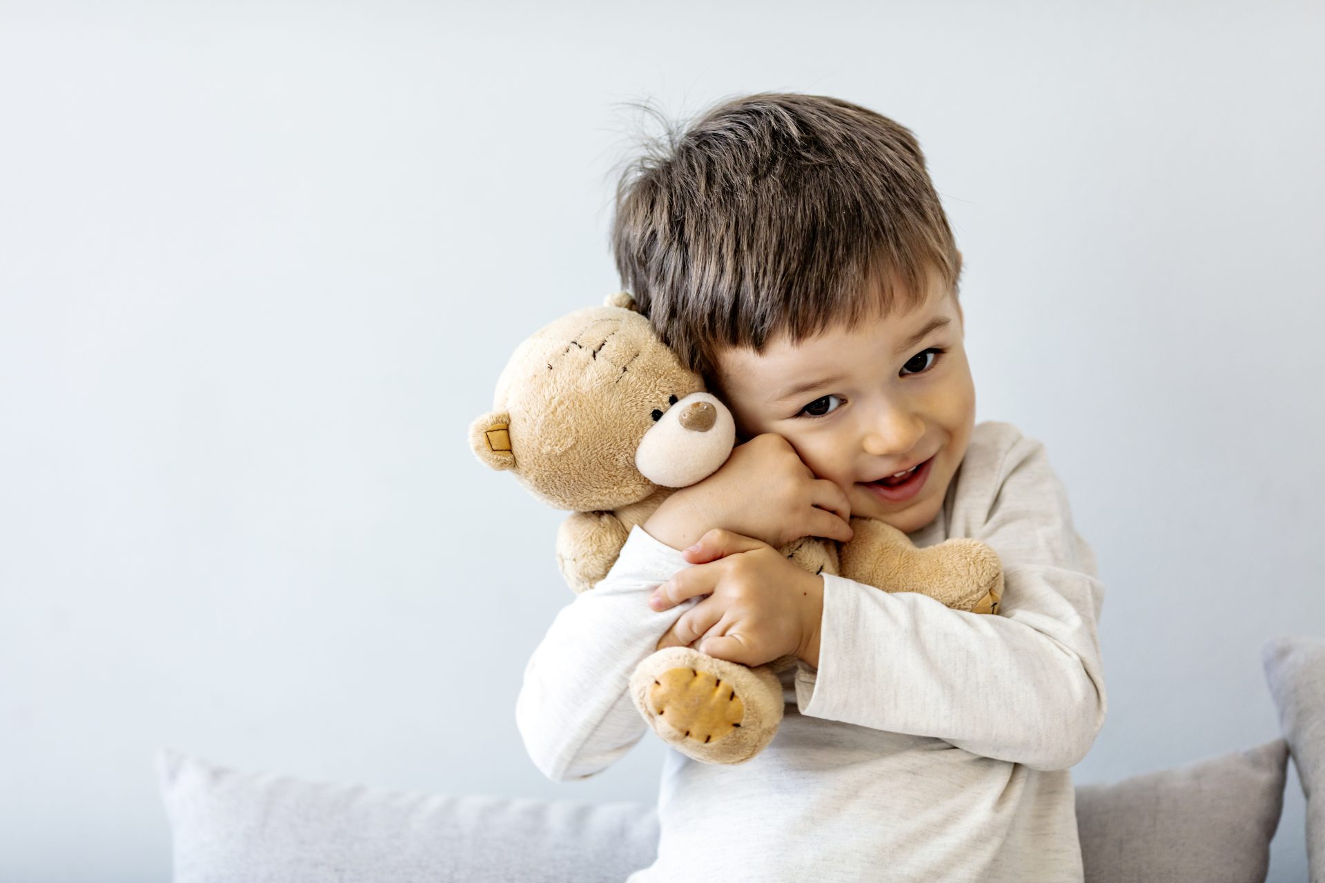 bambino piccolo con maglia bianca stringe al petto peluche