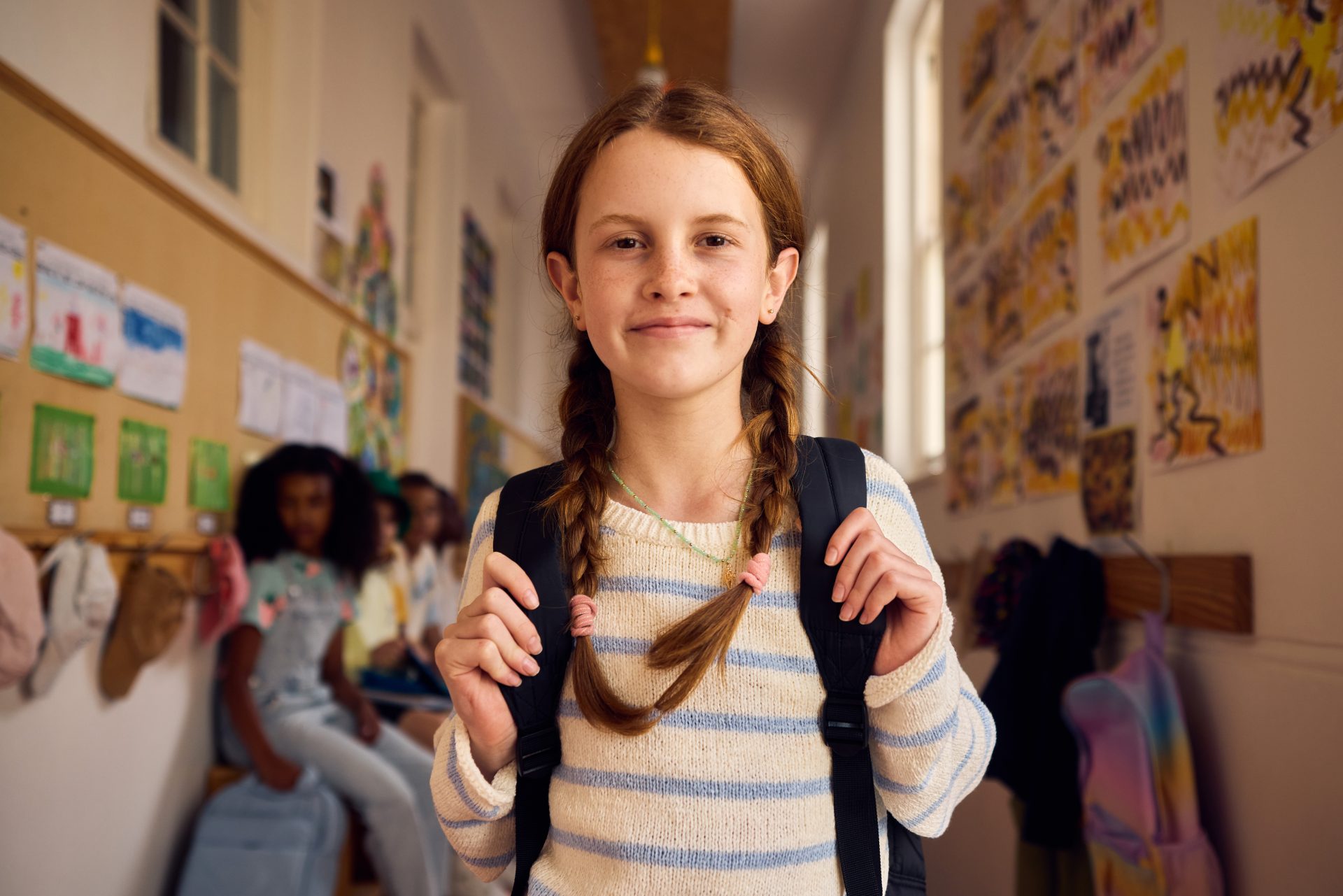 bambina con trecce e zaino nel corridoio di scuola