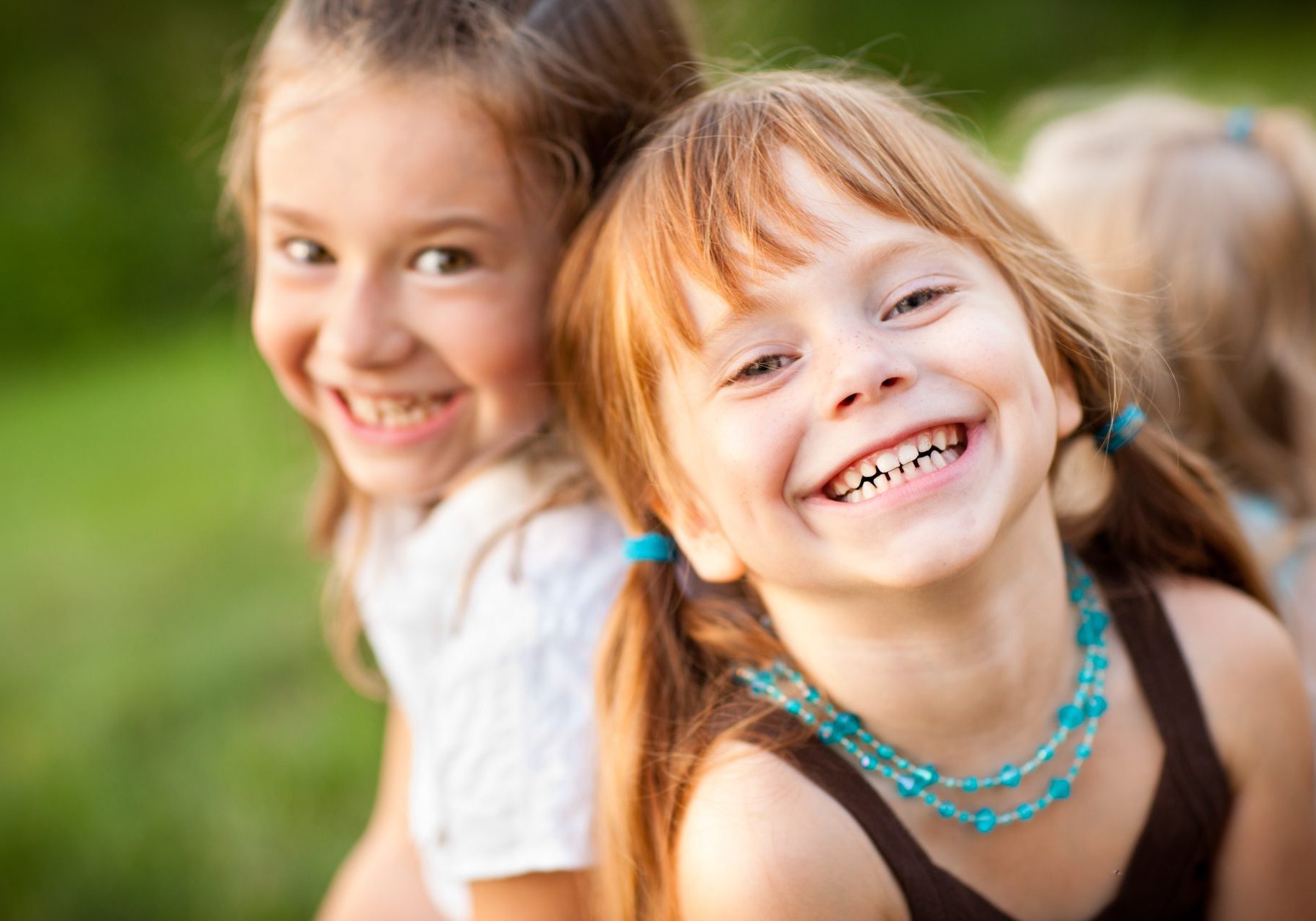 due bambine sorridenti con capelli lunghi biondi