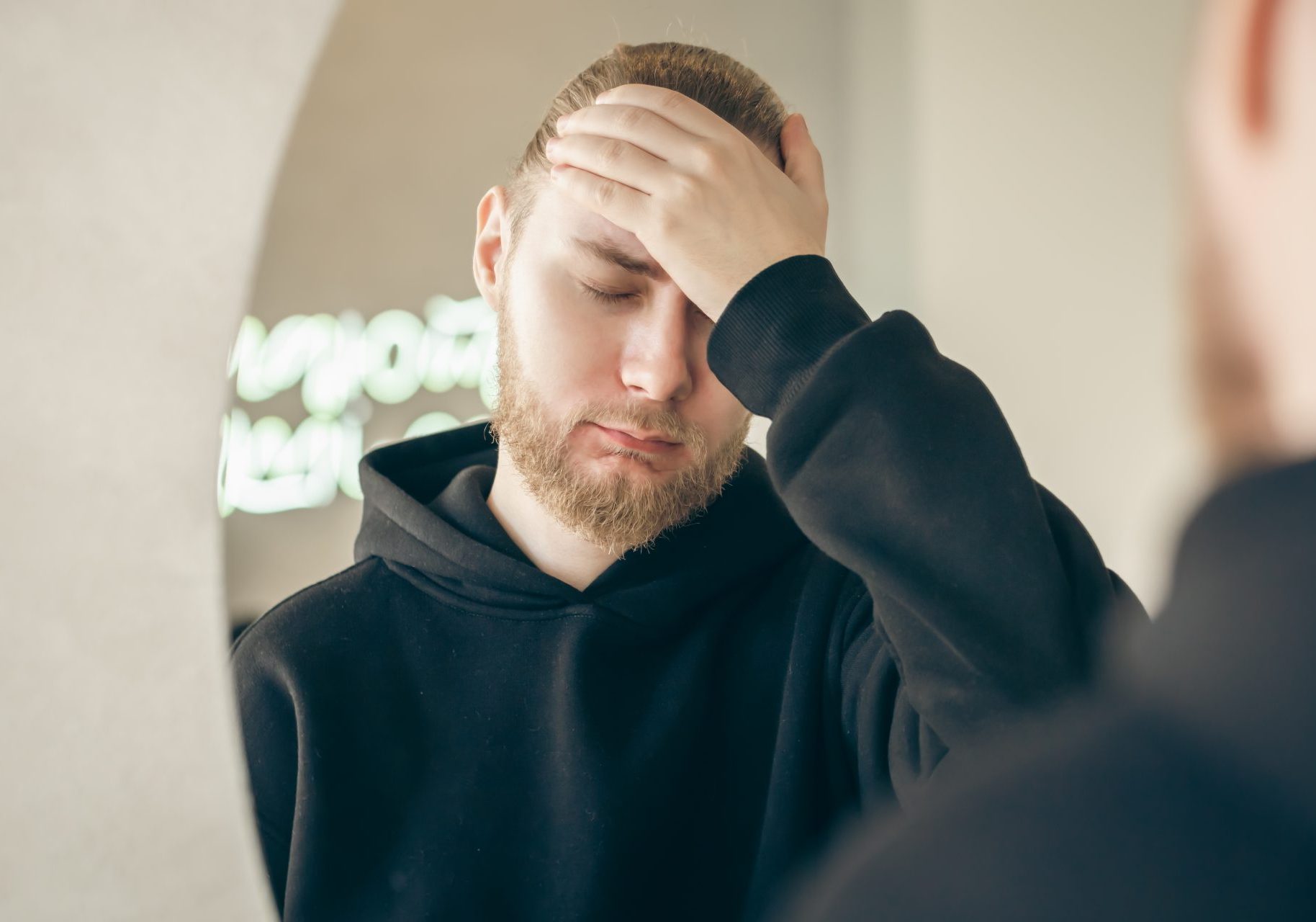 ragazzo con barba triste davanti allo specchio