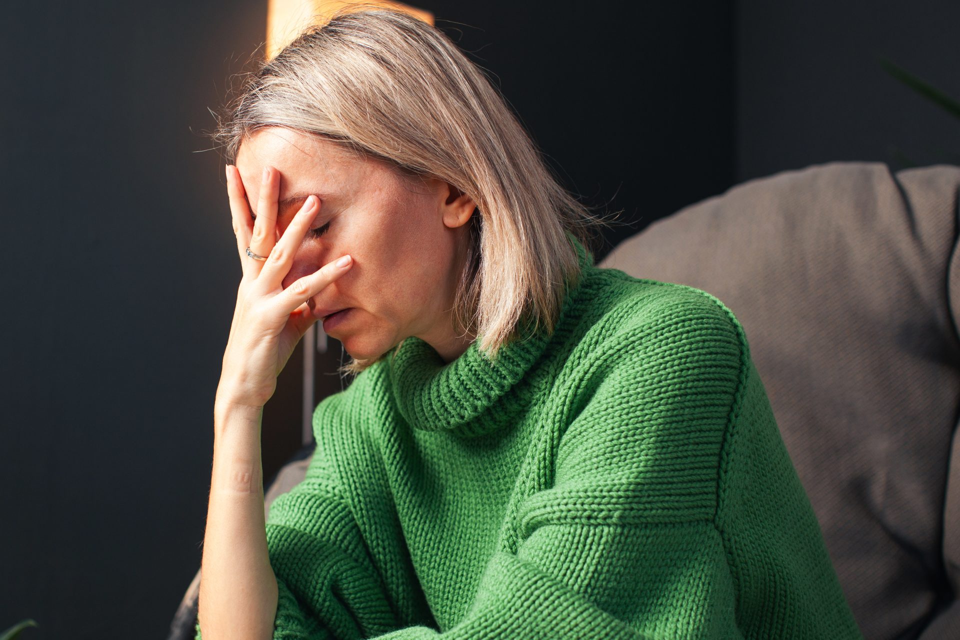 donna bionda stanca seduta con mano sul volto
