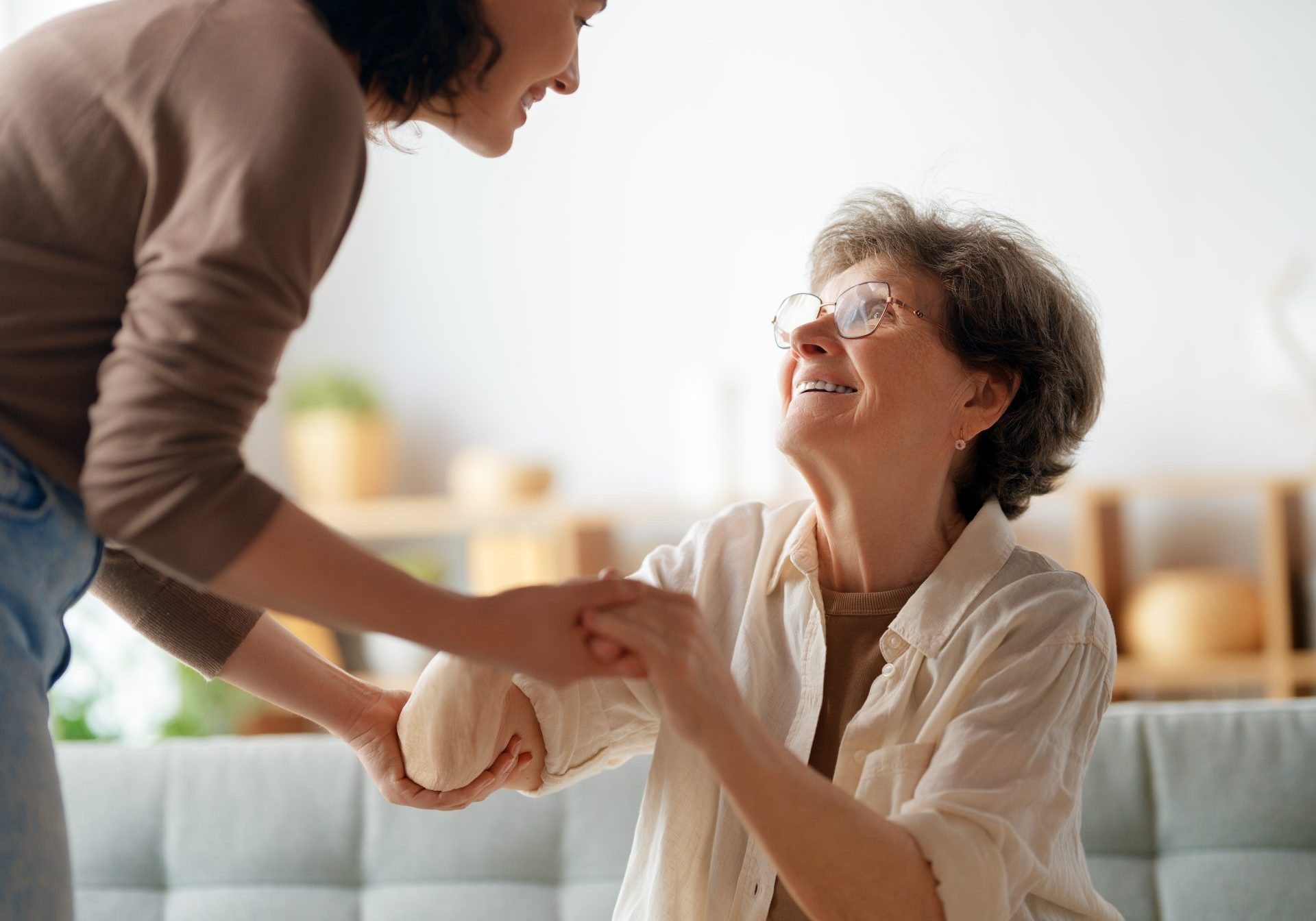 giovane donna caregiver sorridente tiene le mani di donna anziana