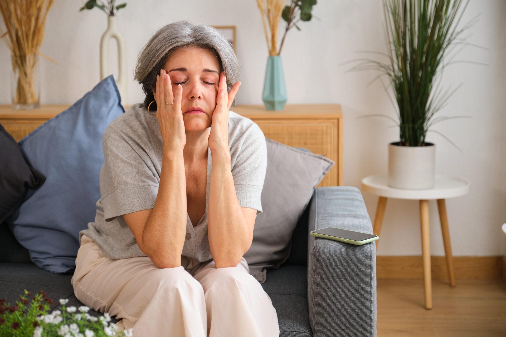donna stanca seduta sul divano si tocca il viso 
