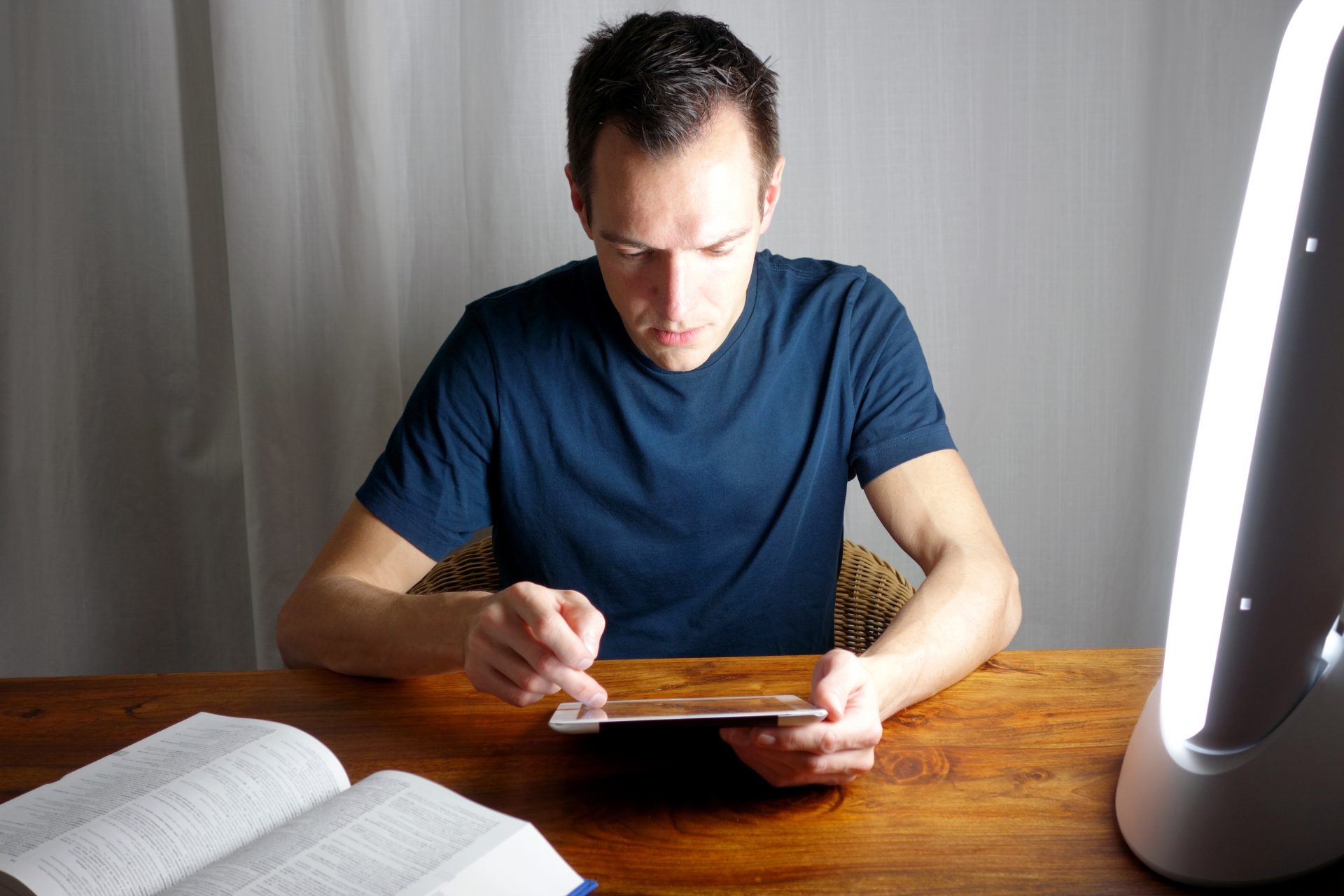 uomo utilizza tablet davanti a lampada per fototerapia