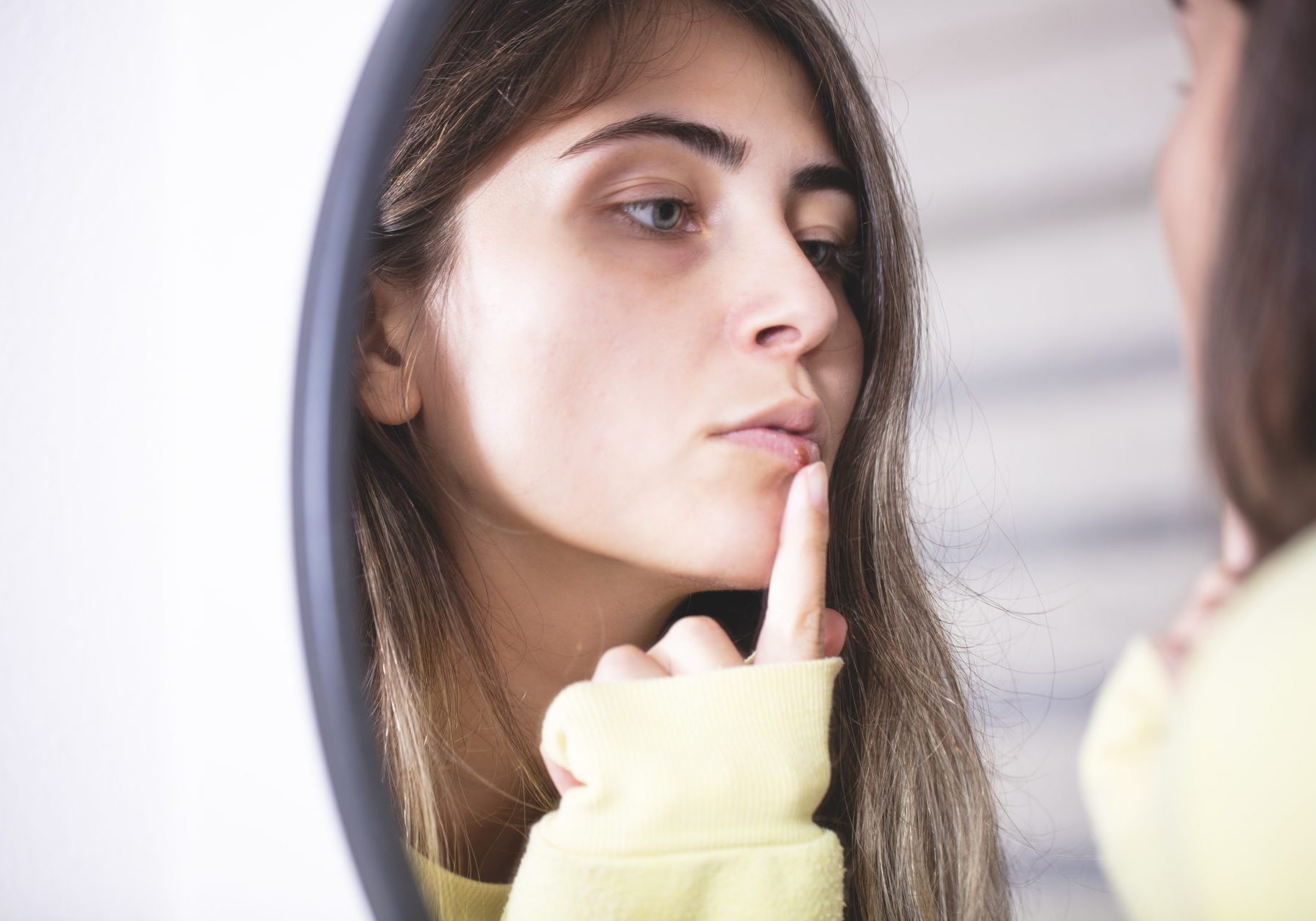 donna controlla herpes labiale allo specchio