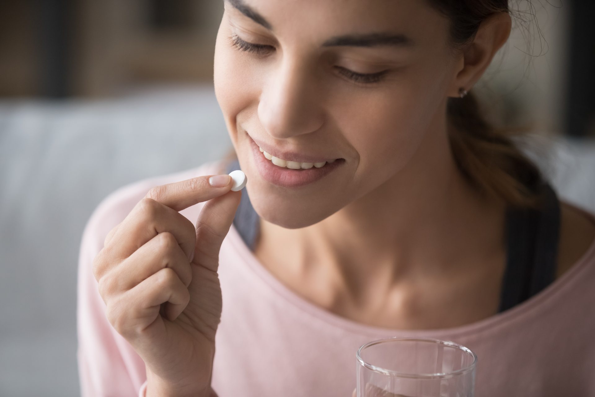 donna tiene pillola e bicchiere d'acqua