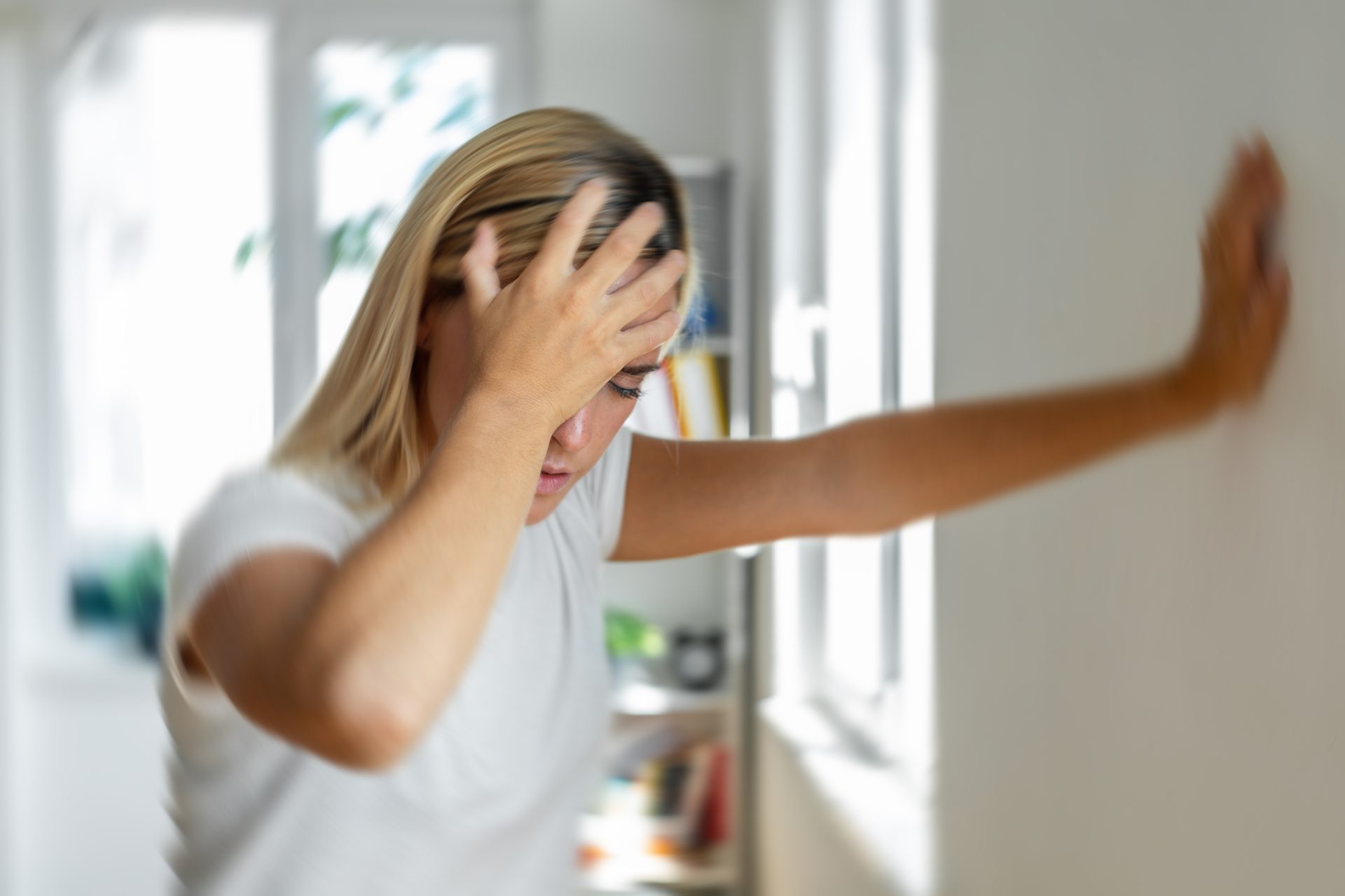 giovane donna con mal di testa appoggia mano alla parete