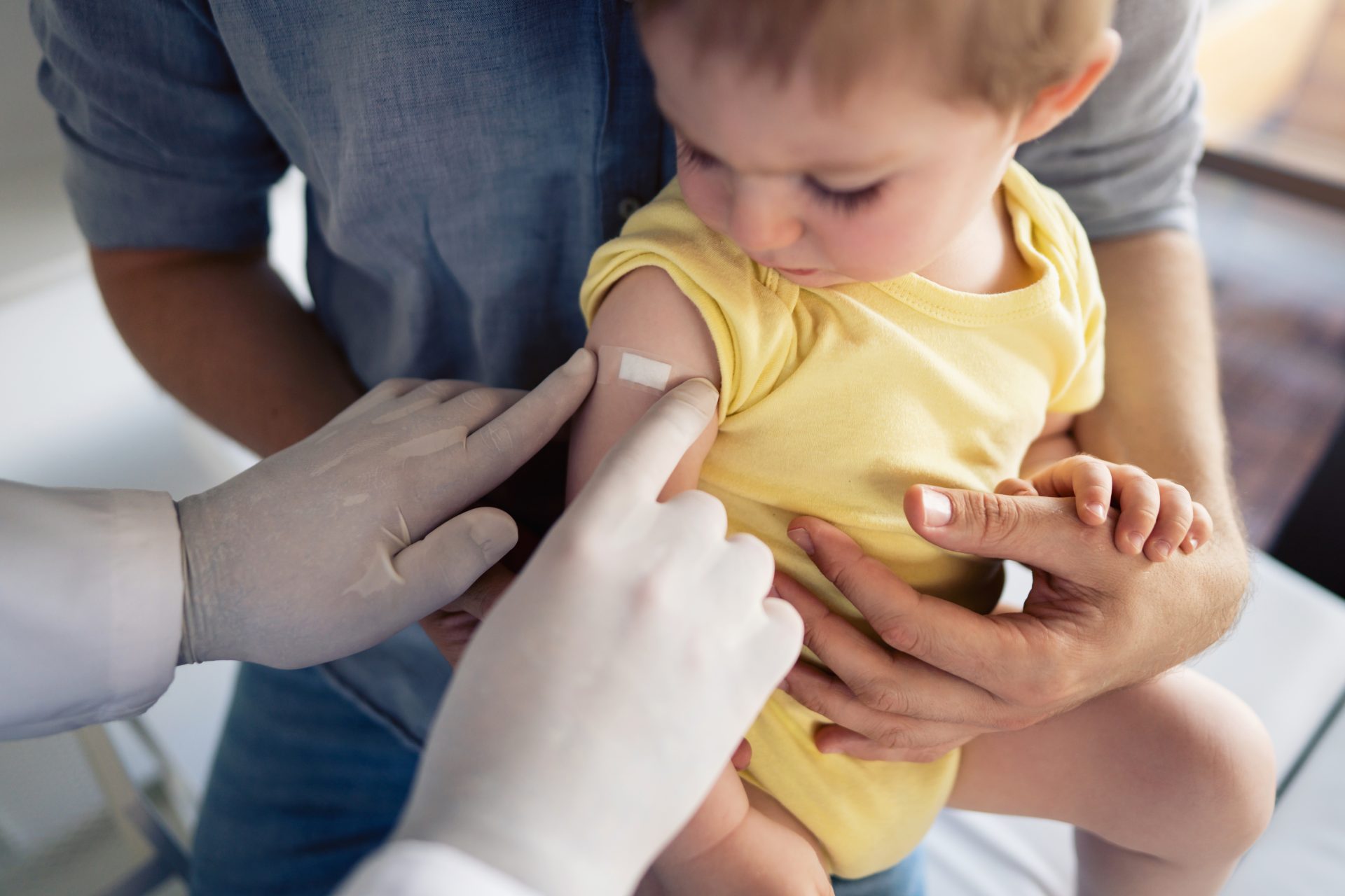 operatrice sanitaria mette cerotto su spalla bambino piccolo dopo vaccinazione