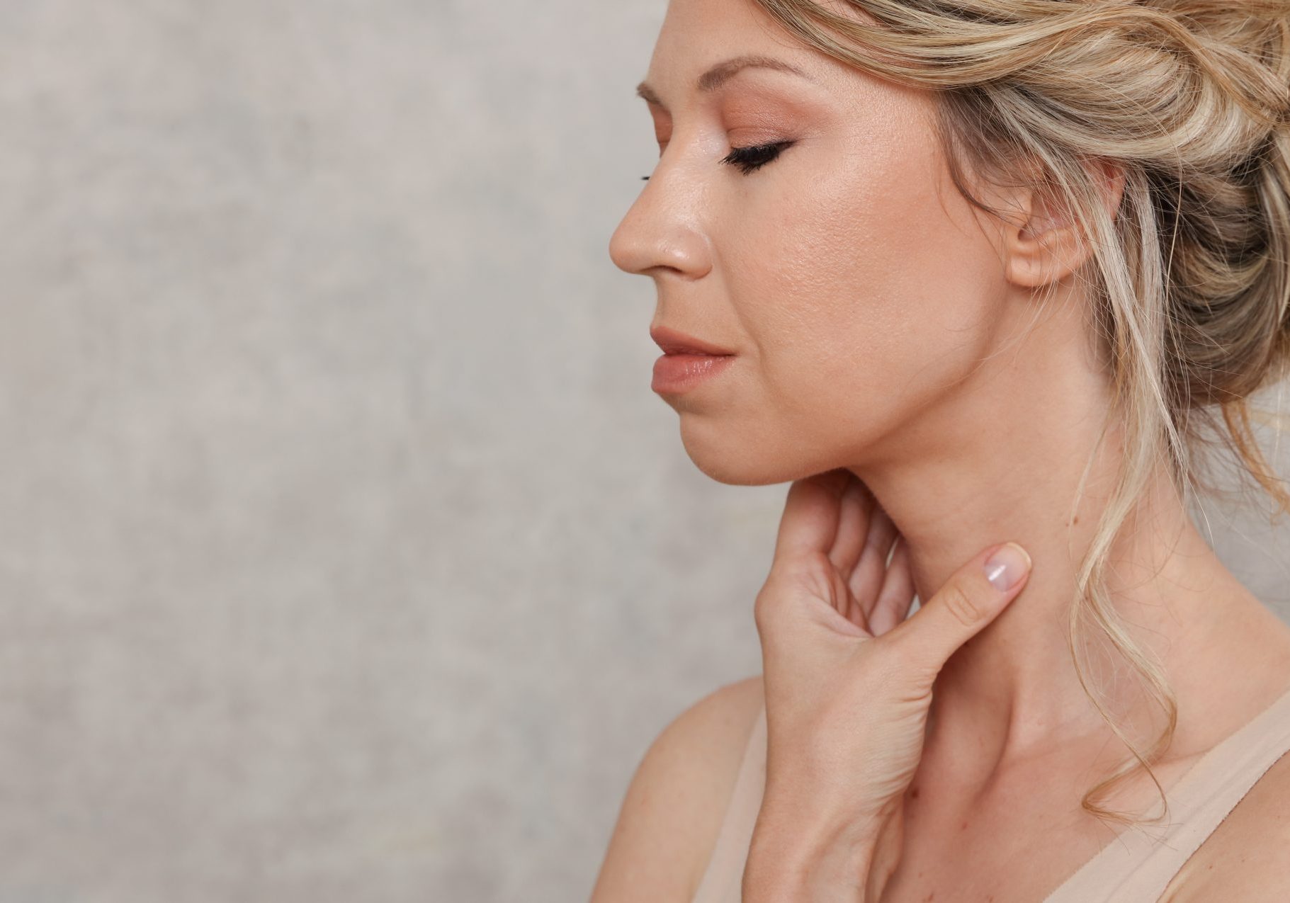 donna bionda si tocca il collo con una mano