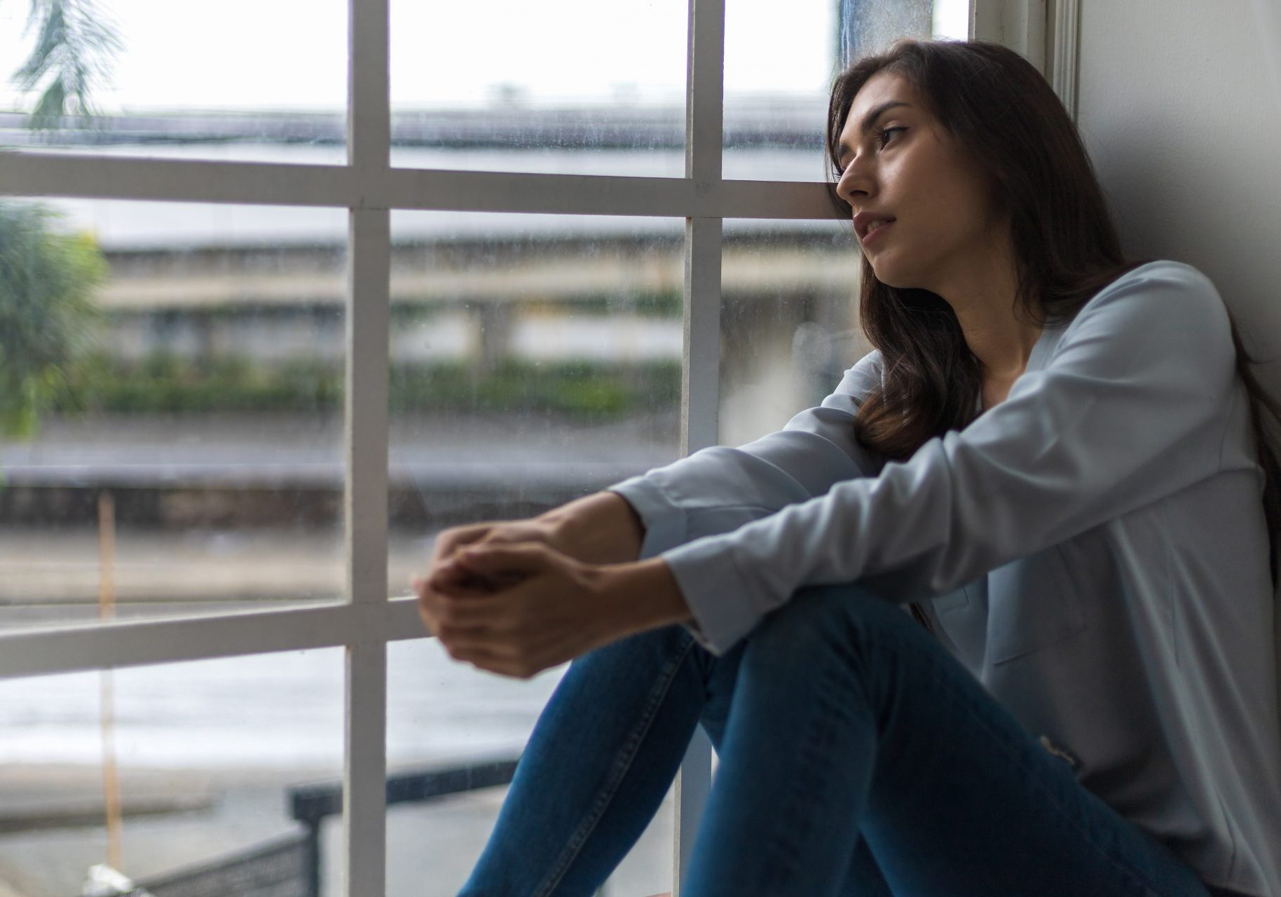 giovane donna triste alla finestra