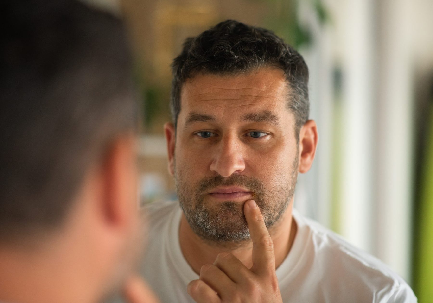 uomo guarda herpes labiale allo specchio