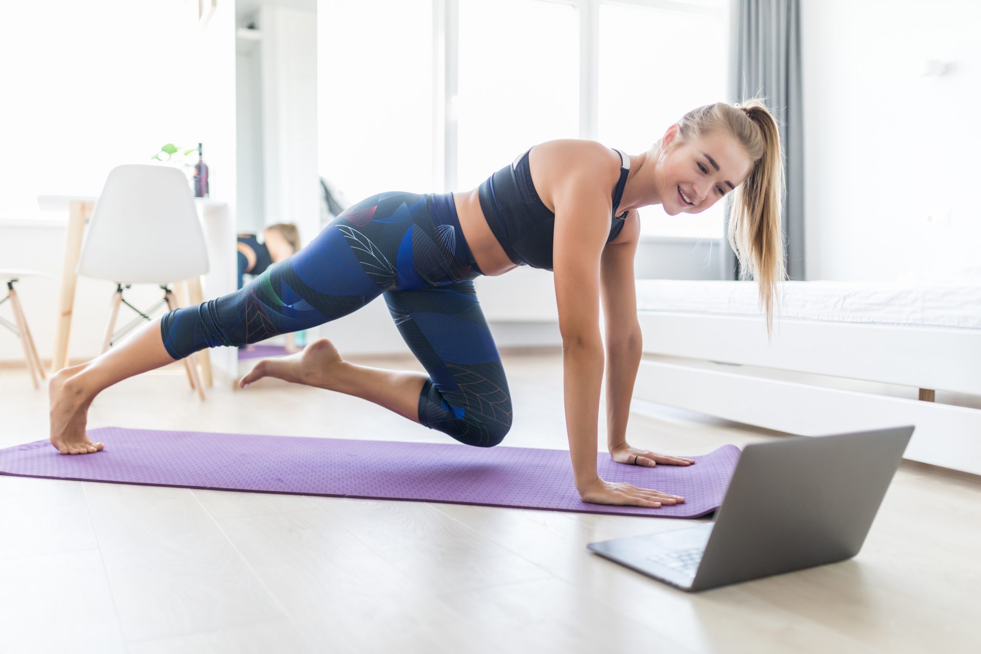 ragazza fa pilates sul tappetino guardando lezione al computer