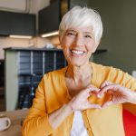 donna anziana fa simbolo del cuore con le mani