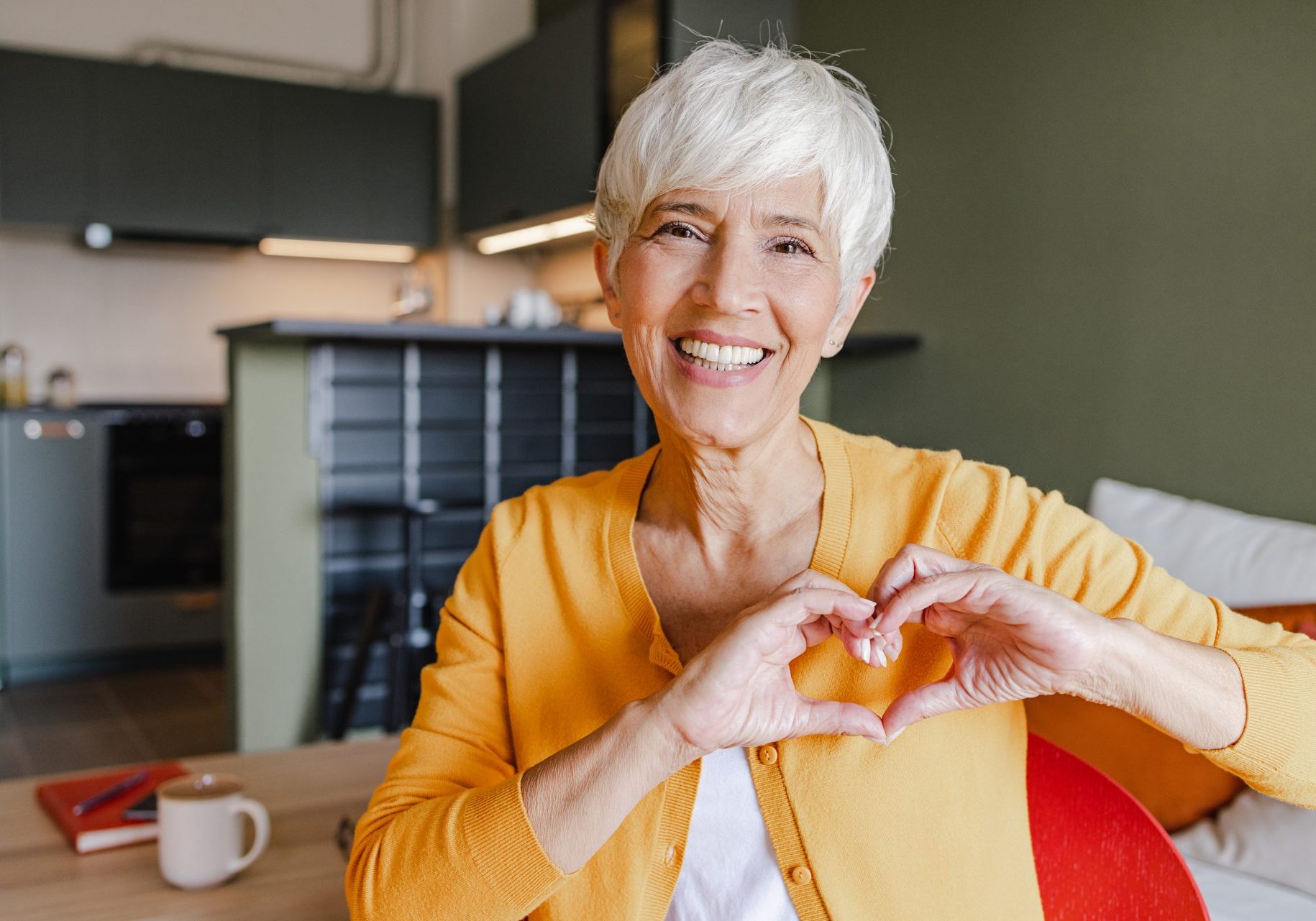 donna anziana fa simbolo del cuore con le mani