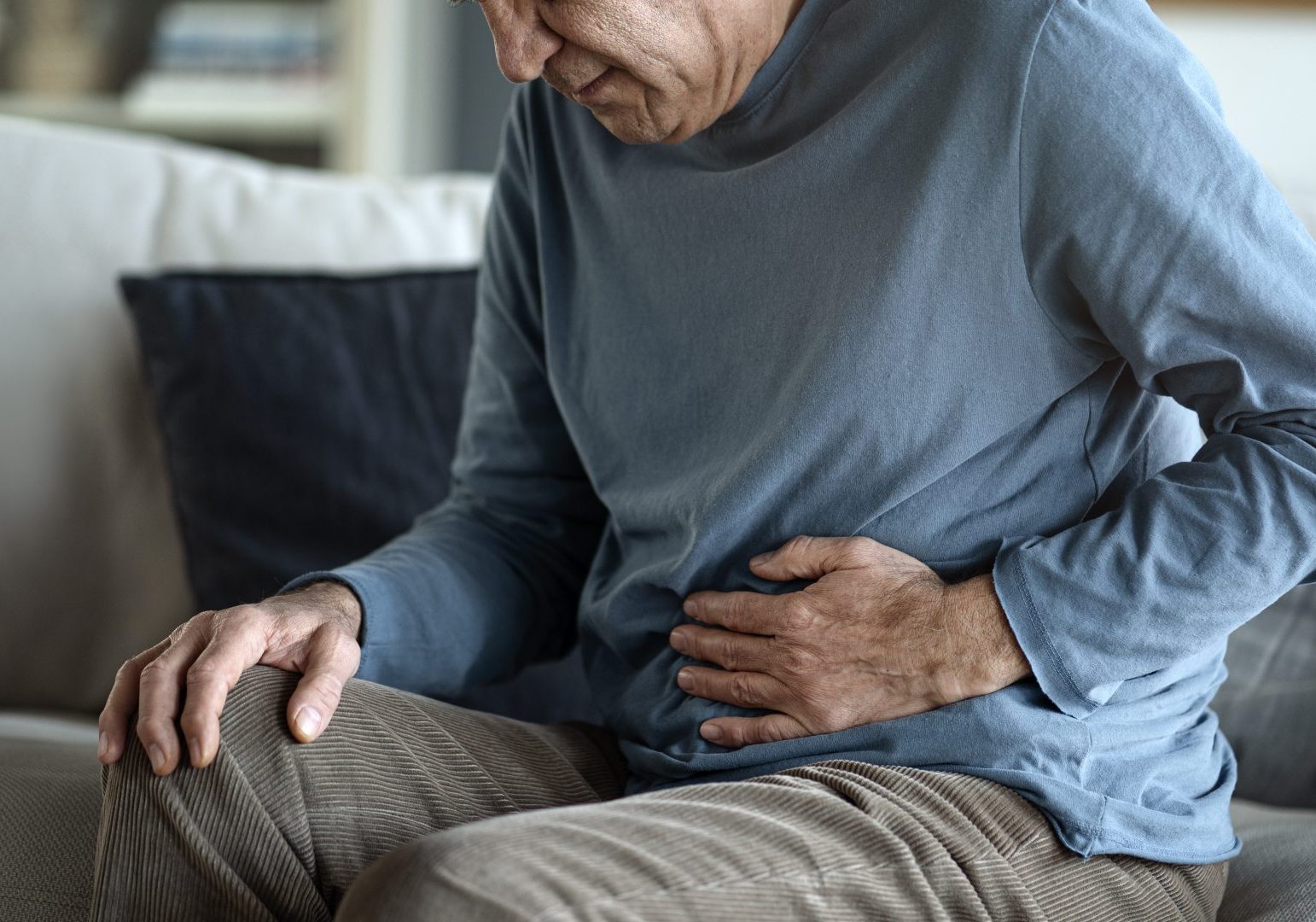 uomo anziano tocca addome dolente con la mano