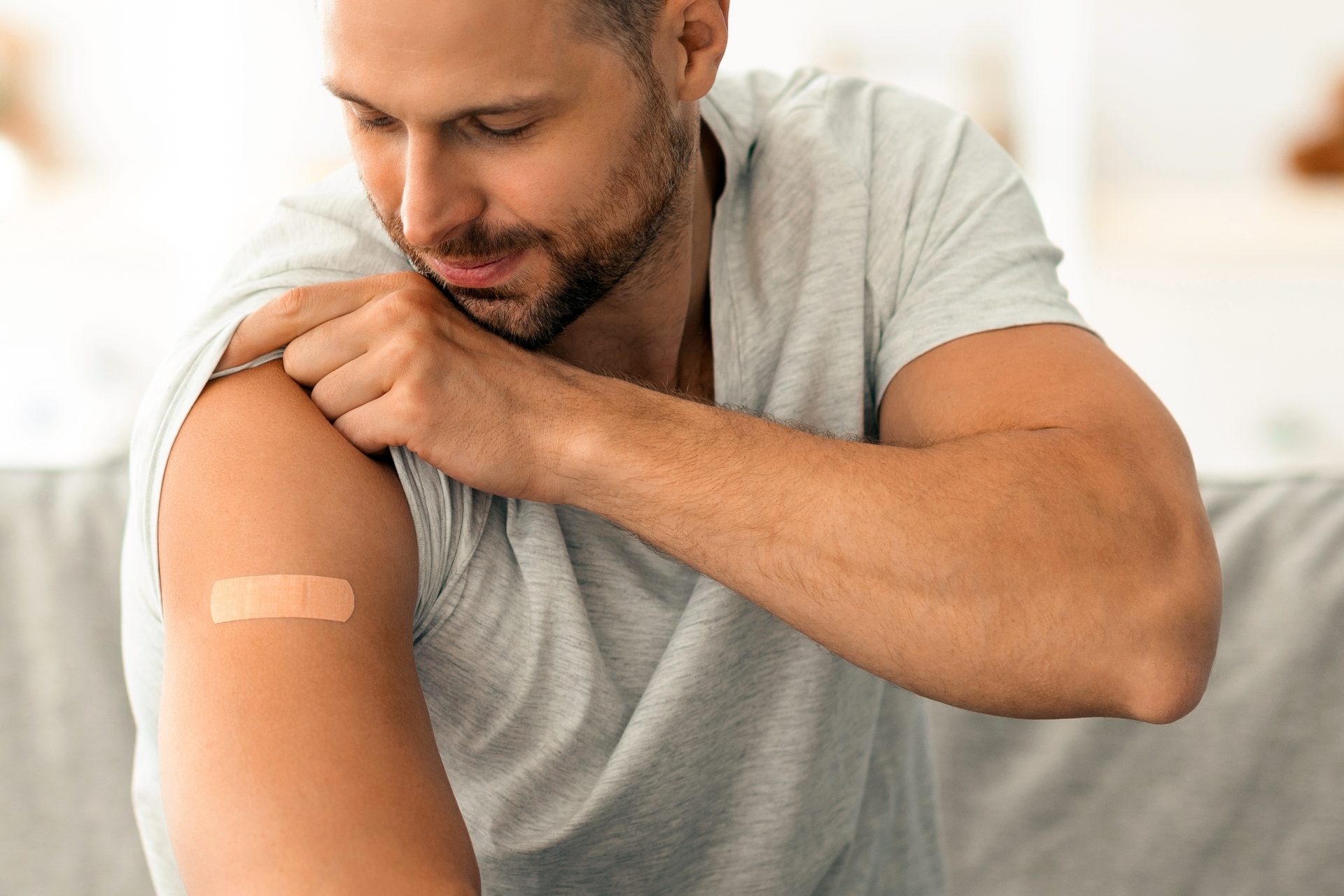 uomo guarda cerotto sul braccio dopo vaccinazione