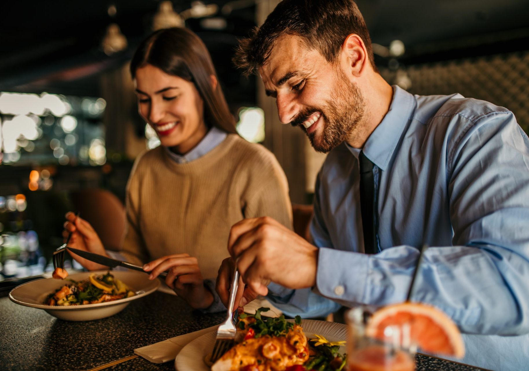 uomo e donna sorridenti mangiano carne