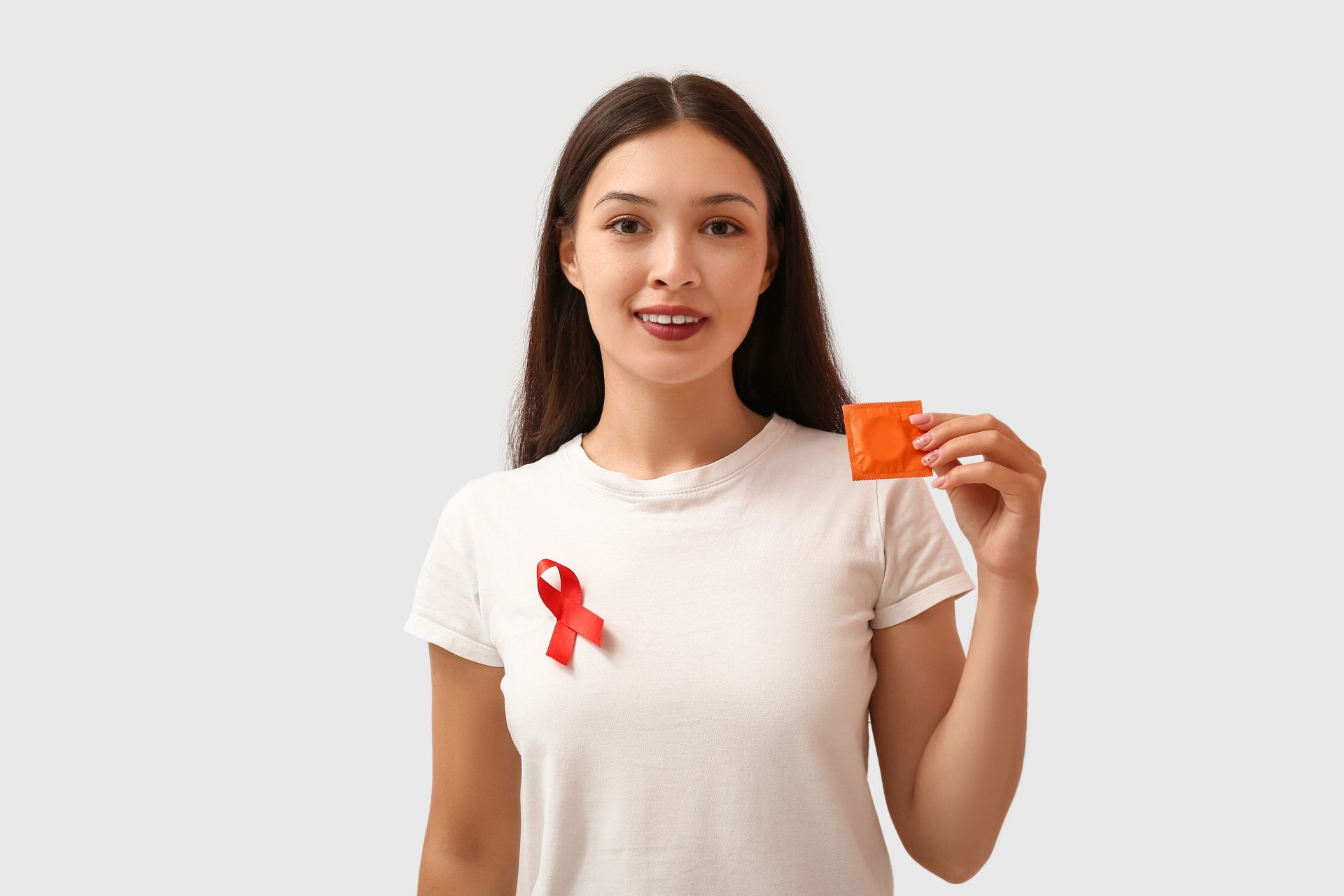 giovane donna tiene in mano preservativo per prevenzione aids