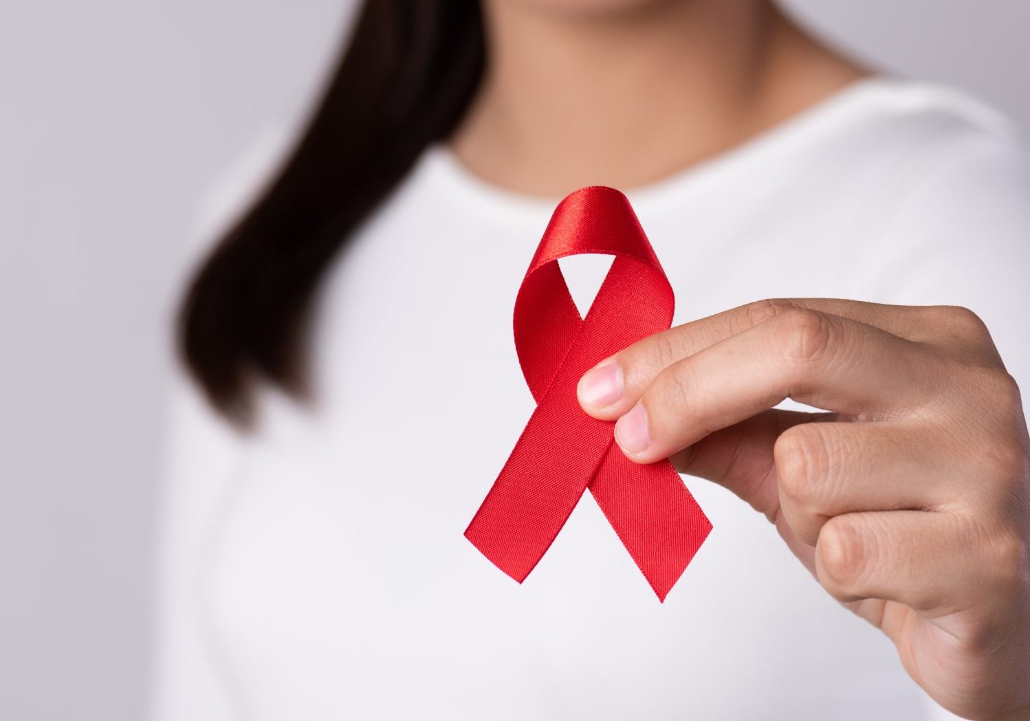 donna tiene in mano fiocco simbolo della lotta all'aids