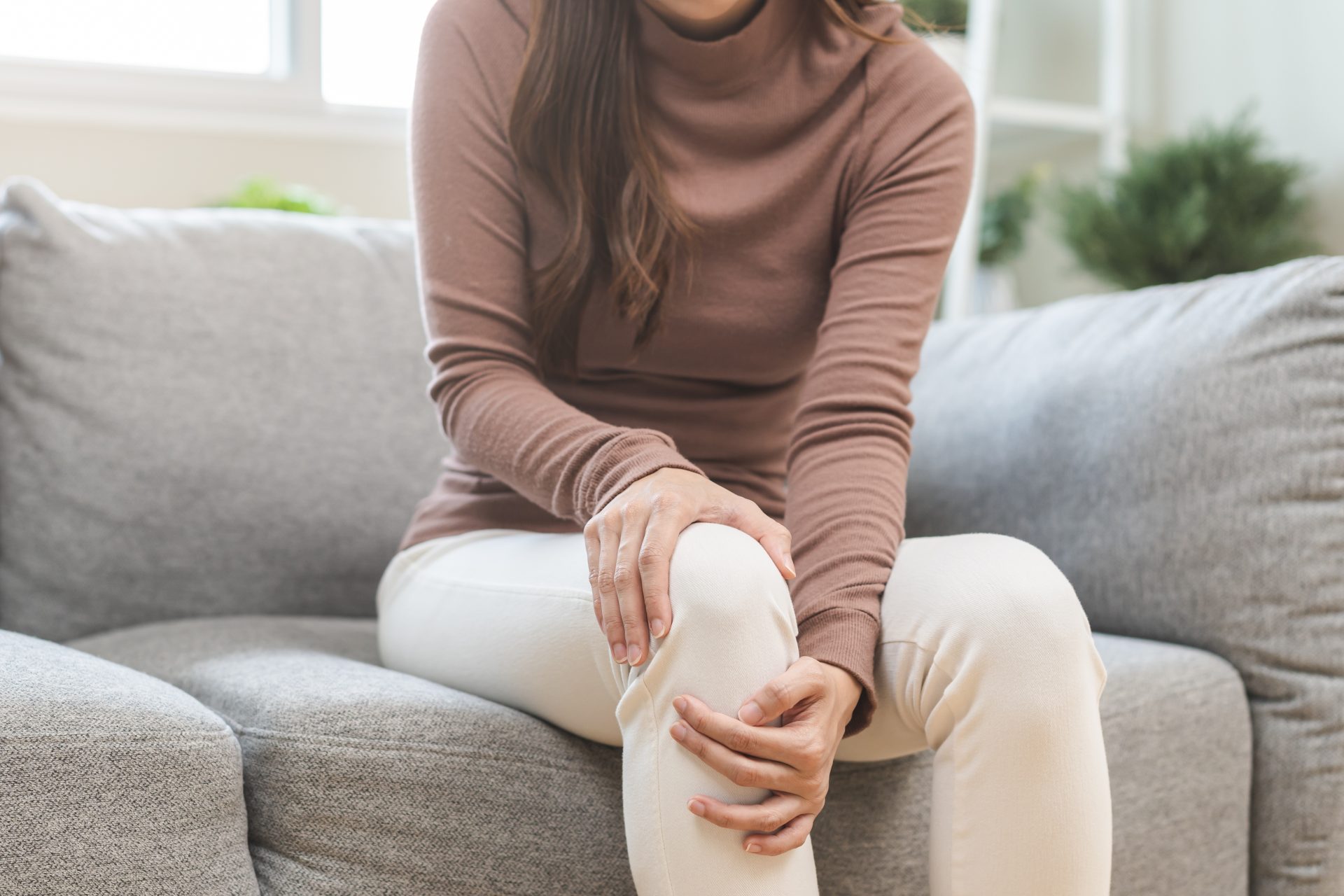 donna seduta sul divano con dolore al ginocchio