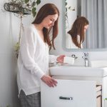 donna prende confezione dal cassetto del mobile del bagno