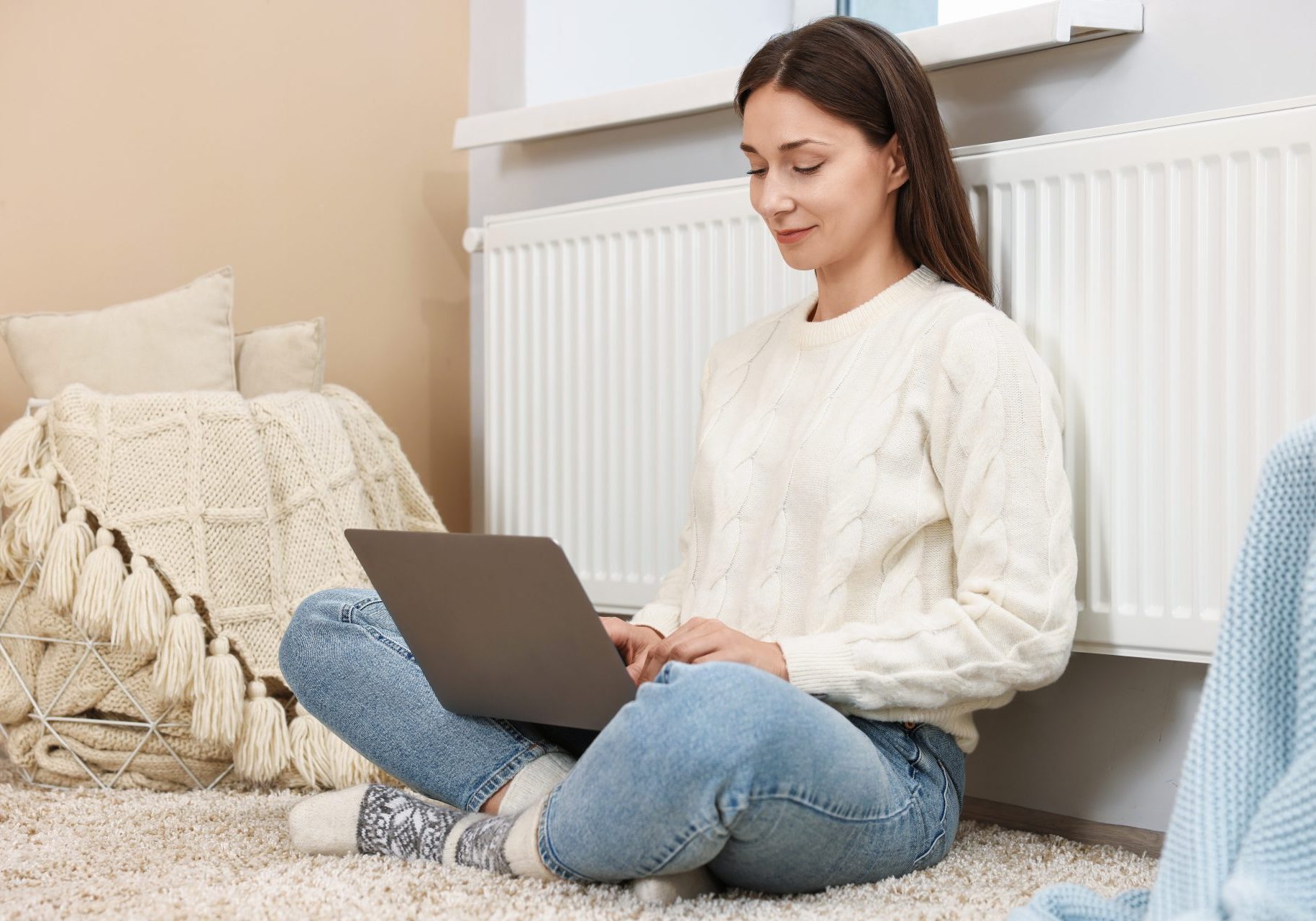 giovane donna seduta con le spalle al termosifone