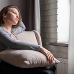 giovane donna pensierosa guarda fuori dalla finestra