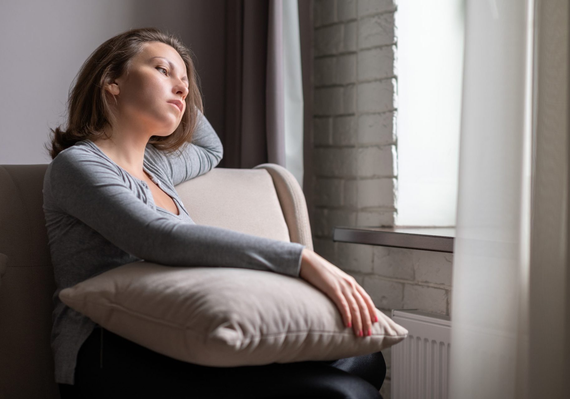 giovane donna pensierosa guarda fuori dalla finestra