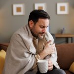 uomo ammalato con coperta e tazza in mano