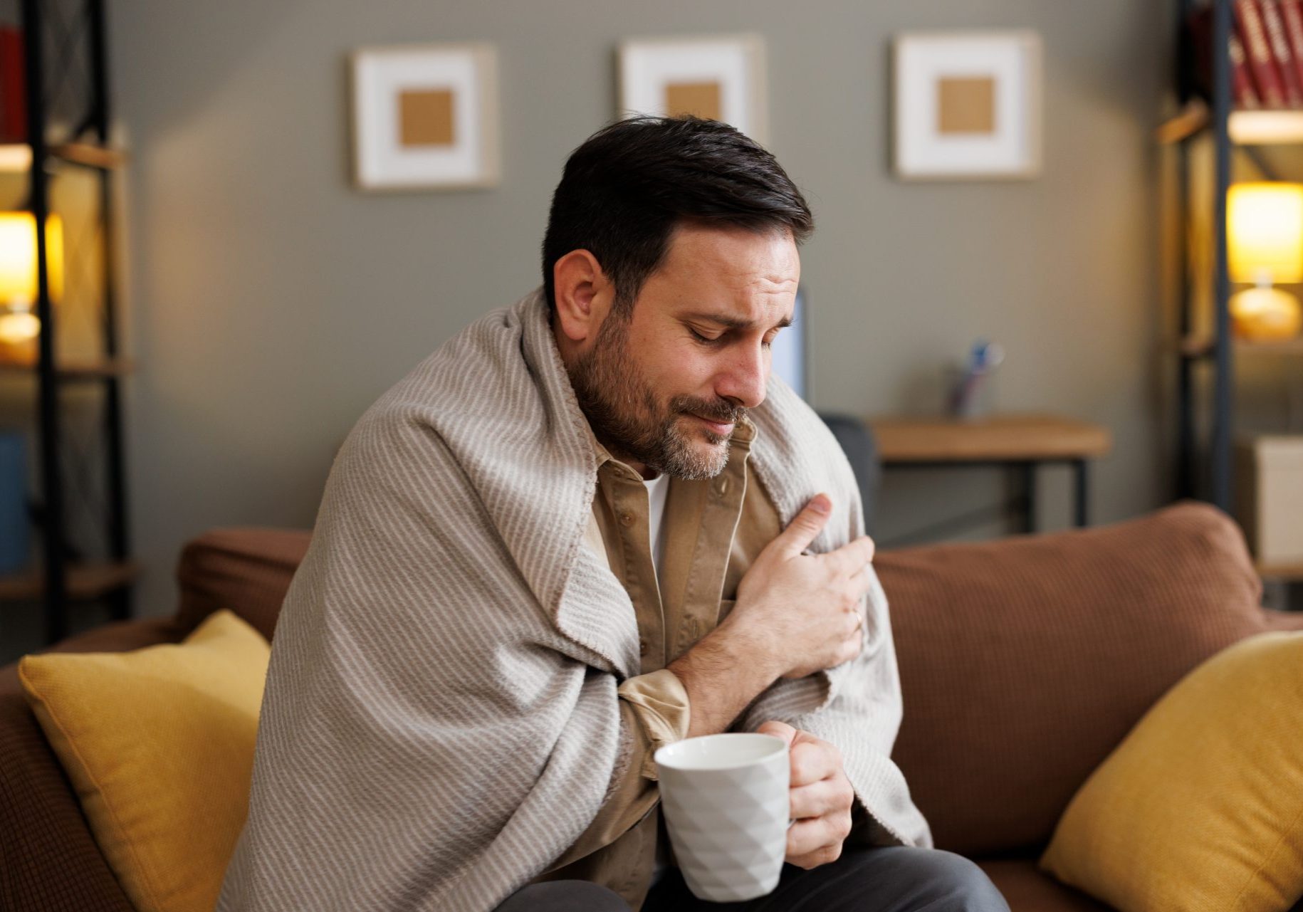 uomo ammalato con coperta e tazza in mano