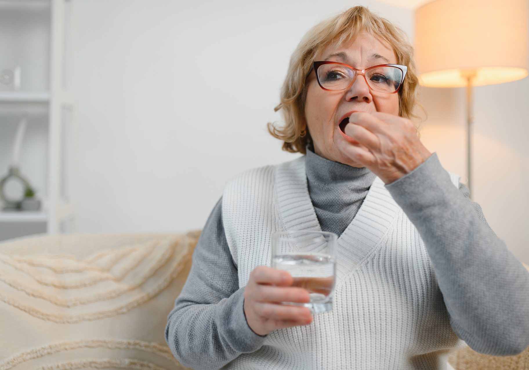 donna anziana prende pillola con bicchiere d'acqua