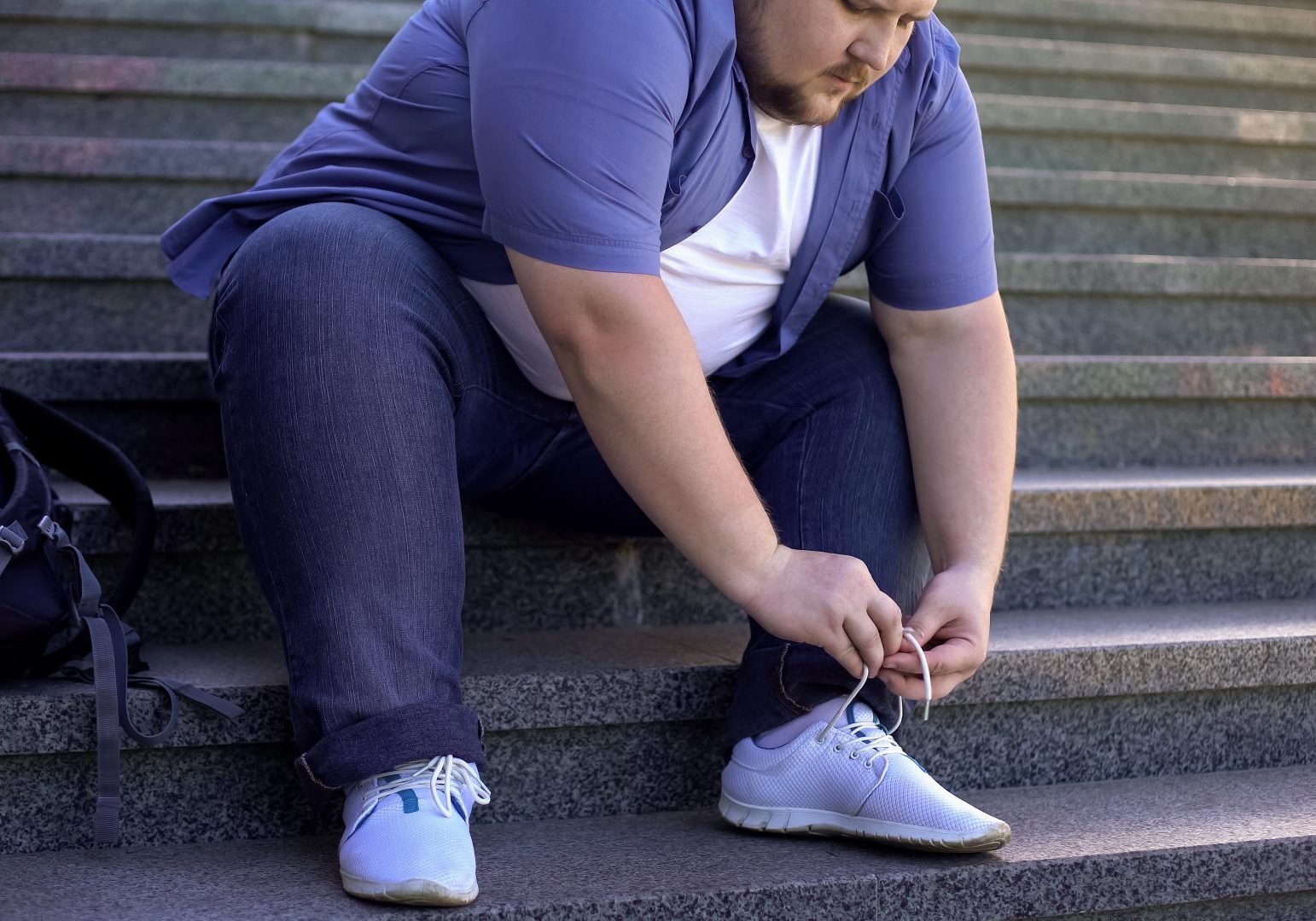 giovane uomo obeso si allaccia la scarpa