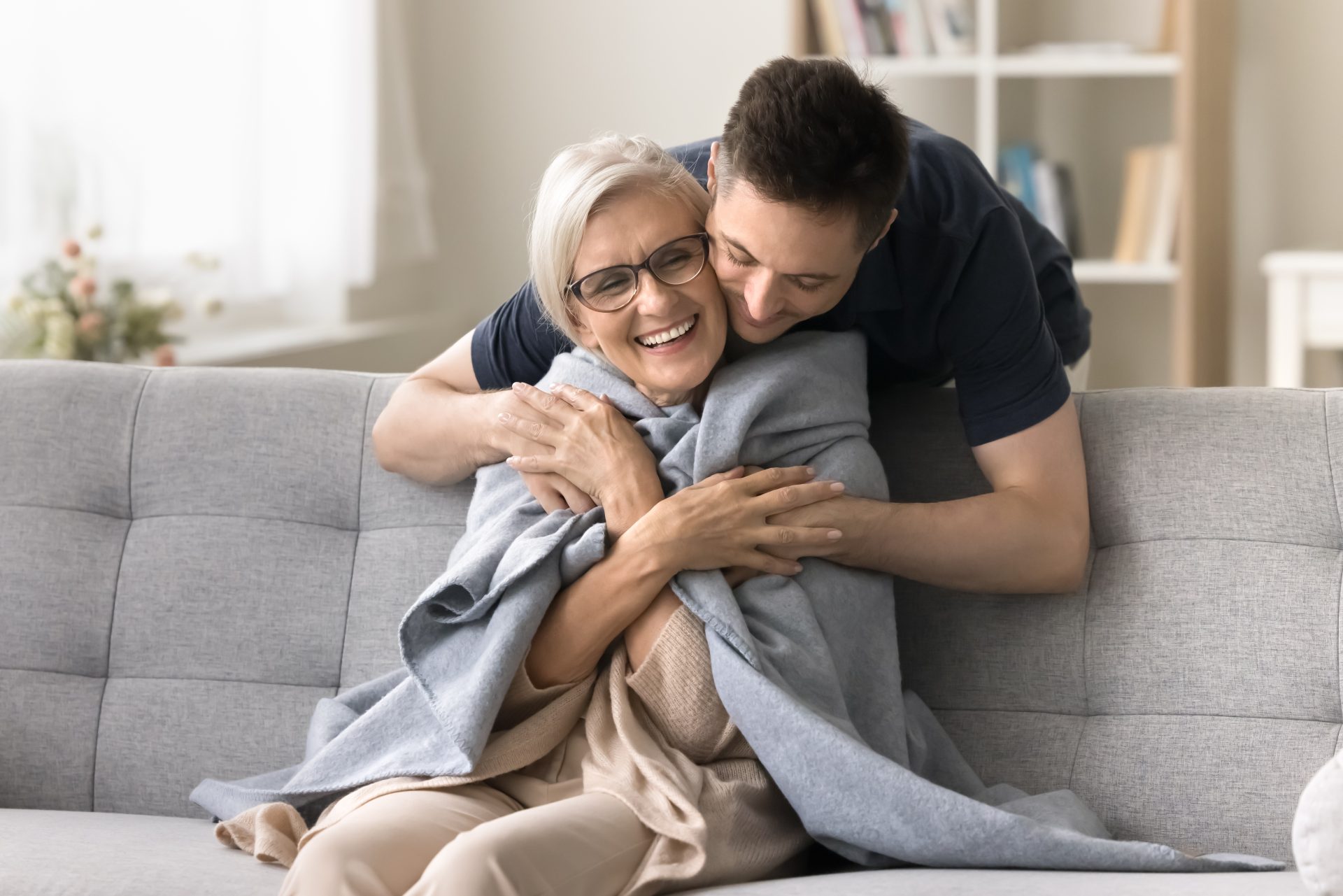 caregiver abbraccia donna anziana sul divano