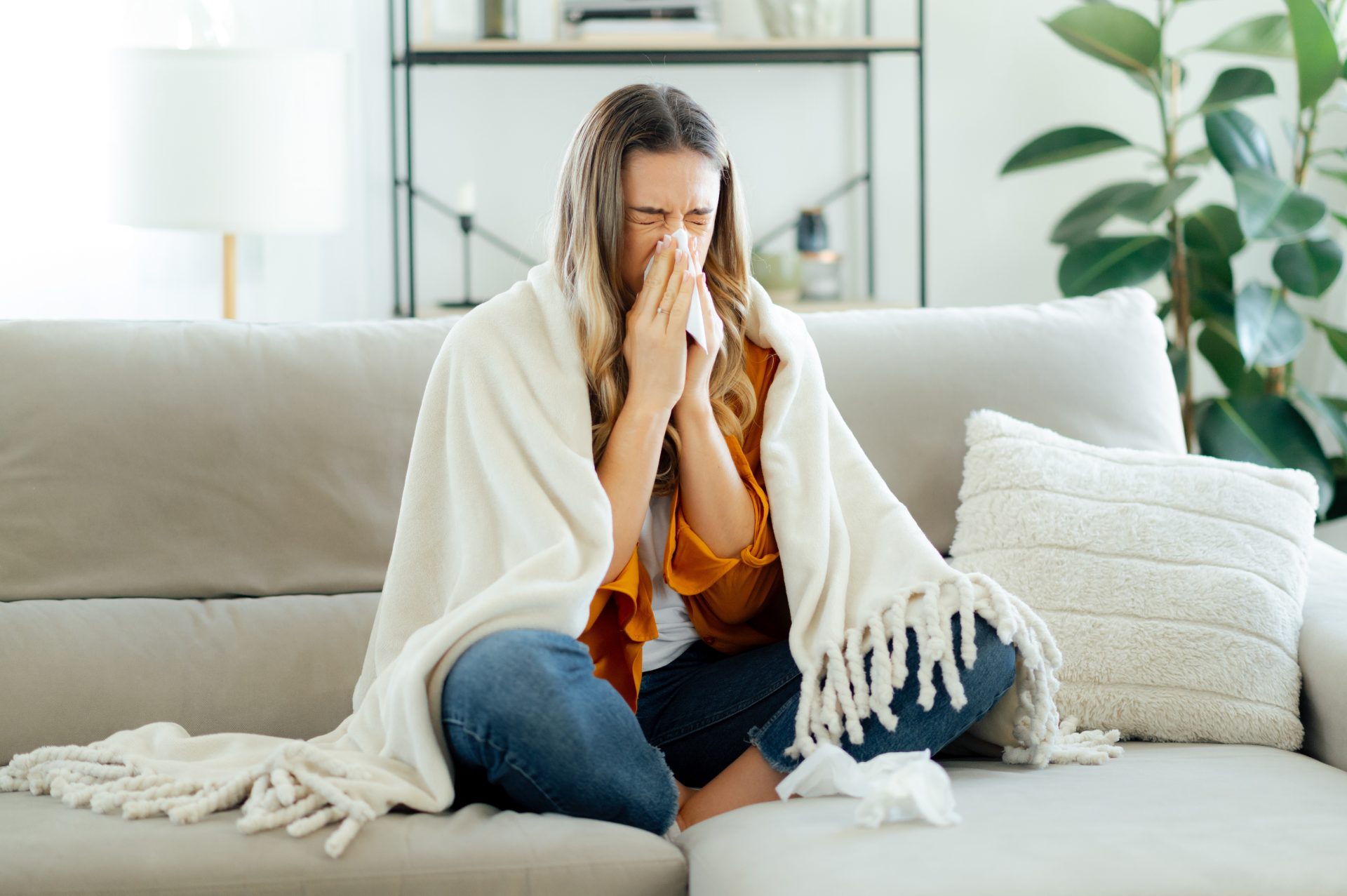 giovane donna con raffreddore con coperta sul divano