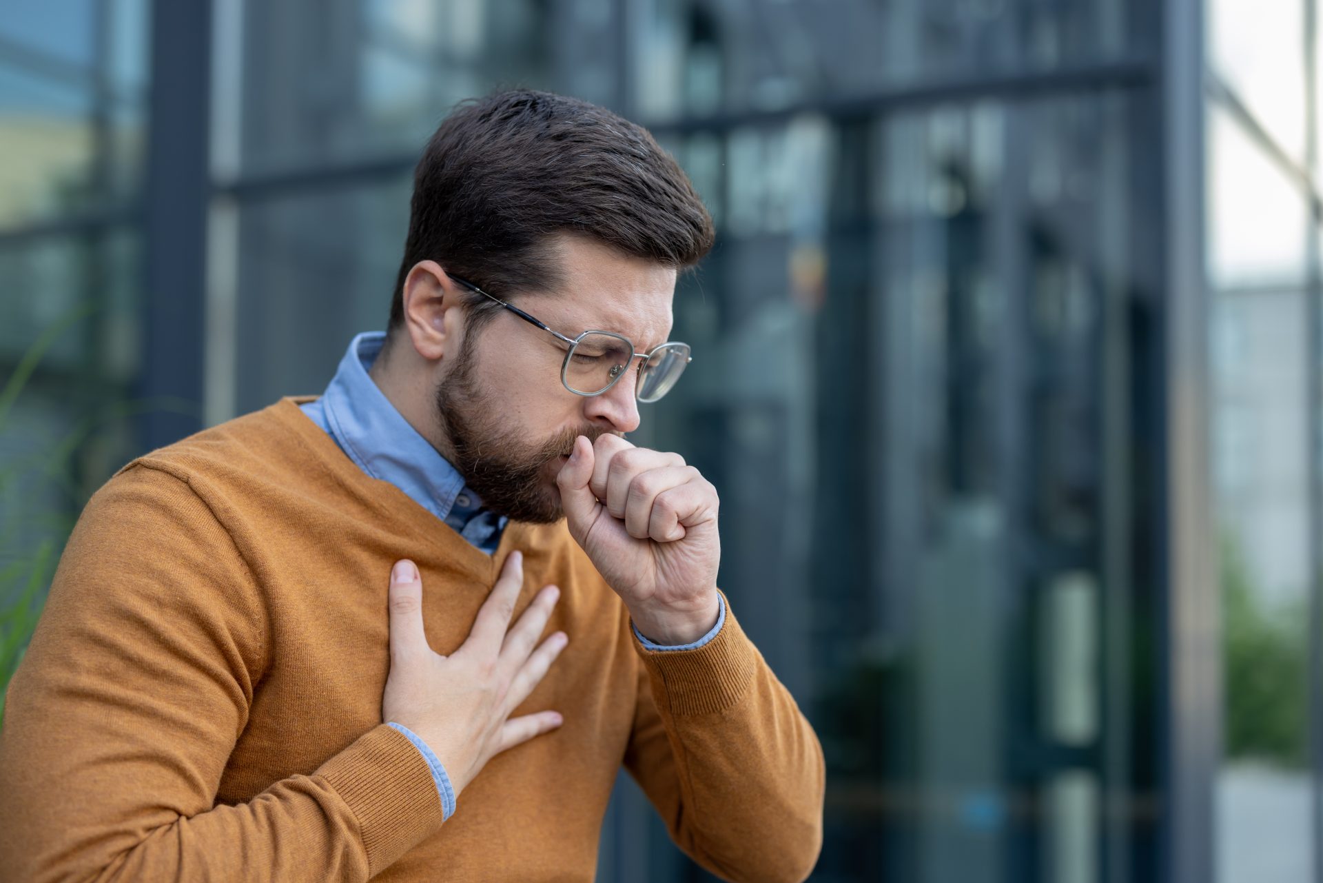 giovane uomo tossisce con mano al petto