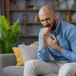 uomo seduto sul divano tossisce