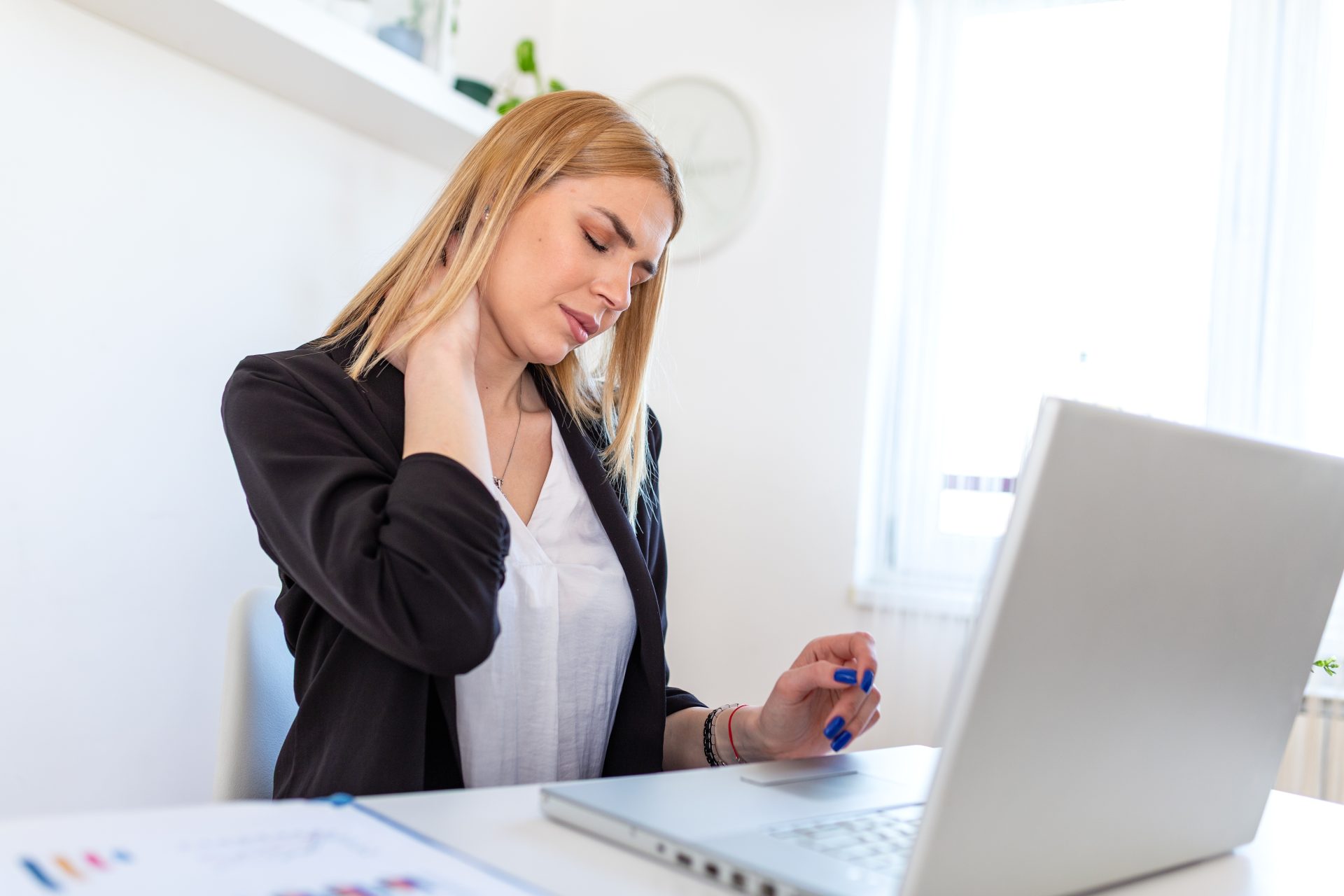 donna con dolore cervicale alla scrivania davanti al computer